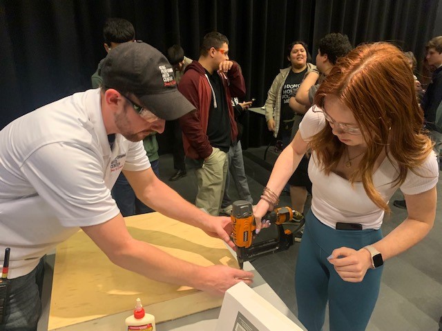An instructor teaches a teen girl using a drill at Backstage Spotlight
