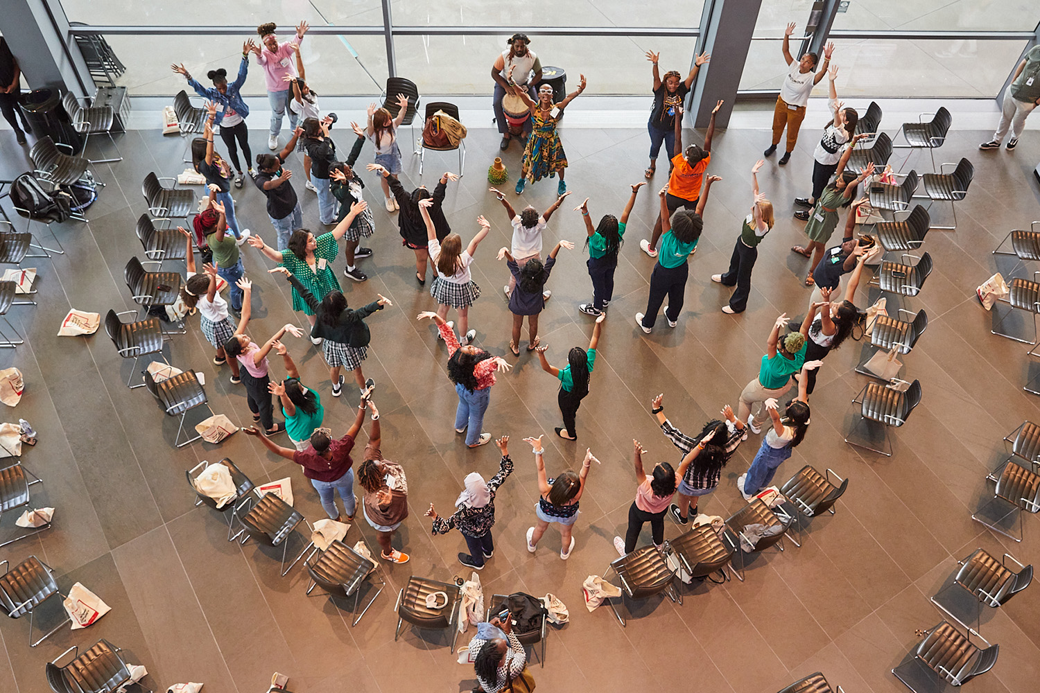 Young women take part in activities at the Young Women's Leadership Conference, view from above of participants standing with their arms raised.